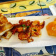 Prawns glazed with fire-roasted tomato sauce are accompanied on the plate by grilled focaccia and orange slices.