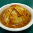 Baked apple enclosed in savory crust in a bowl full of spicy juice