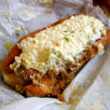 Bunned hot dog smothered with chili, cole slaw, mustard, and onions