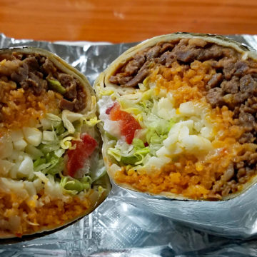 Cross section of a burrito filled with carne asada, cheese, and veggies