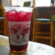 Plastic cup is filled with dark red hibiscus tea, flavored with ginger