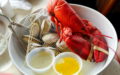 Lobster and steamer clams in a bowl with broth and butter