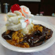 In a paper bowl, a moon pie is the foundation for ice cream, hot fudge, wet walnuts, whipped cream, and a cherry.