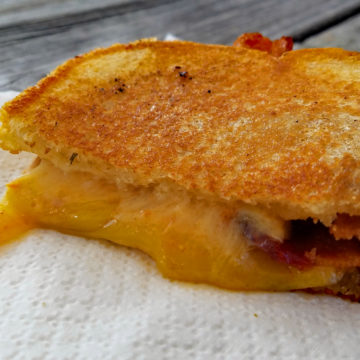 Melted cheese shares space with thick-cut bacon between slabs of butter-griddled toast.