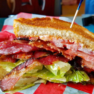 Loaded bacon, lettuce, and tomato sandwich is held together with a toothpick.