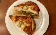 Breakfast sandwich on a jalapeno bagel holds egg, Cheddar, and turkey plus pesto mayo, tomato, and sprouts