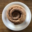 Spiral round pastry on a plate is covered with cinnamon and sugar outside and in