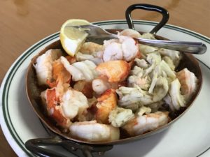 Shrimp, lobster & crab in a pool of butter in a hot copper pan