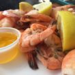 Shell-on shrimp are accompanied by a cup of melted butter for dipping.