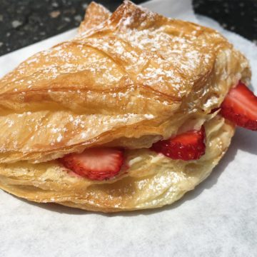 Fragile, light tan baked croissant holds strawberries and pastry cream