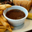Cup of dark, beefy natural gravy for dipping sandwich and fries