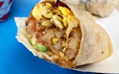 Cross-section of a breakfast burrito shows bacon and eggs, potatoes, cheese, and avocado