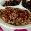 A partitioned plate holds pork chopped into a heap of pieces, some soft, some crisp-edged