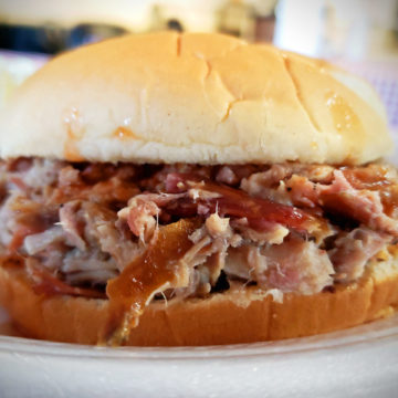 Hacked-up, smoke-cooked pork is dressed with a minimal amount of BBQ sauce inside a bun.