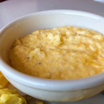 A bowl of grits, creamy and orange with cheese