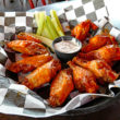 Broad basket holds sauce-brushed chicken wings along with blue cheese dressing and celery sticks ... must-eat Buffalo honor roll