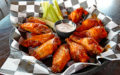 Broad basket holds sauce-brushed chicken wings along with blue cheese dressing and celery sticks ... must-eat Buffalo honor roll
