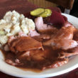 Hot ham slices are bathed in clove gravy and sided by beets and potato salad