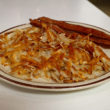 Hash browns, browned and crisp, with bacon in the background