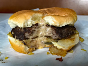 A bitten burger reveals molten cheese inside. ... molten cheeseburger of Minneapolis