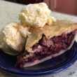 Wedge of pie filled with multiple kinds of berry is a la moded with two scoops of ice cream