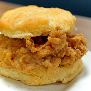Crusty gold fried chicken is sandwiched by a buttermilk biscuit