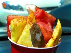 Red party cup holds chunks of fresh fruit dusted with hot pepper