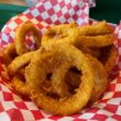 In a red drive-in basket, onion rings are crisp and golden-brown