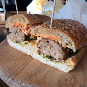 Sub sandwich holds large meatballs festooned with carrots and other vegetables typical of a banh mi sandwich