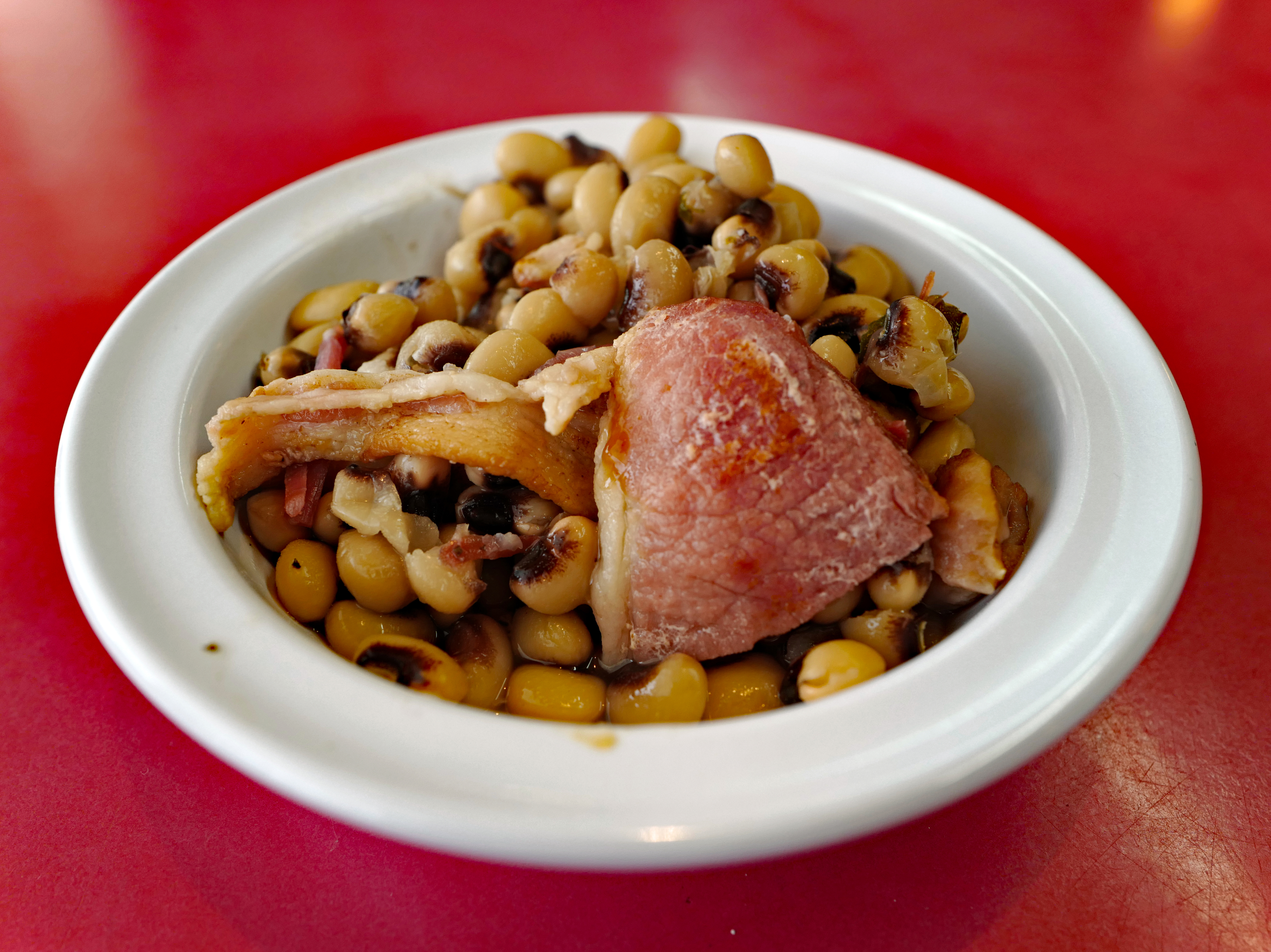 Bowl of blackeyed peas includes slices of pink ham