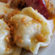 Close view of pierogi glistening with butter and speckled with bits of onion