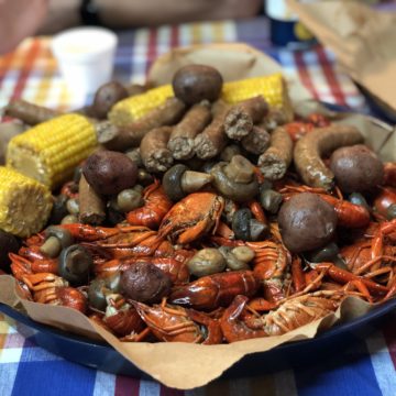 Broad dish holds crawfish with corn, potatoes, mushrooms, and sausage.