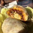 Cross section of a breakfast burrito shos bacon and eggs plus cheese