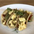 A trio of tacos hold eggs and roasted potatoes.
