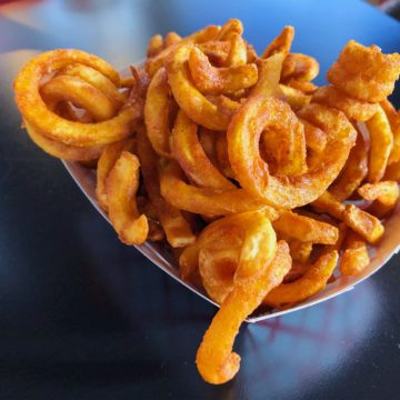 A cardboard boat piled with curly fries