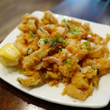 Plate of fried calamari mixed with pickled vegetables and chili sauce