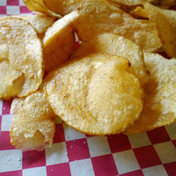 Crisp circular potato chips on a red-checked tablecloth