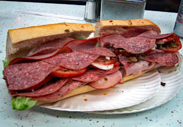 Submarine sandwich overloaded with cold cuts, cheese, and garnishes