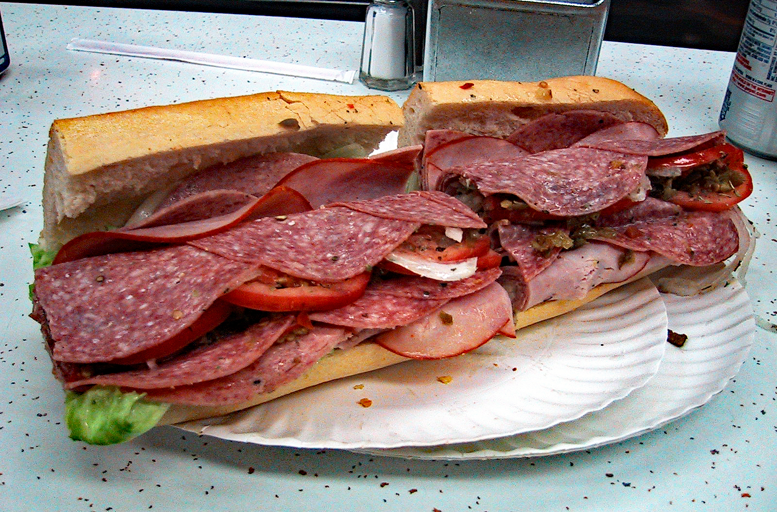 Submarine sandwich overloaded with cold cuts, cheese, and garnishes