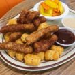 Plate holds finger steaks and tater tots along with cups of gravy and fry sauce for dipping.