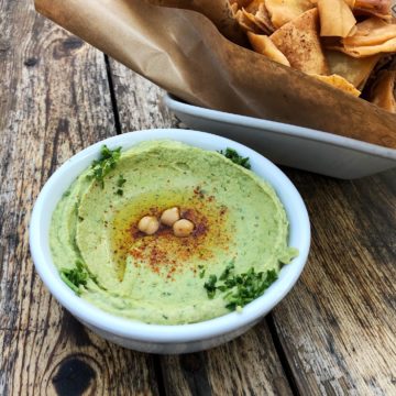 Bowl of hummus fraught with cilantro and jalapeno pepper