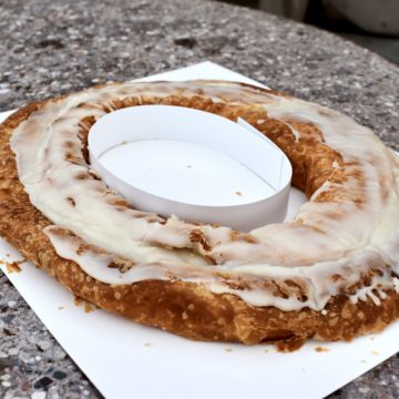 A whole apple kringle with sugar icing, on a counter ready to cut
