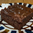 Square of deep dark chocolate cake, extra sweet becaue of its Coke infusion, is topped with sweet chocolate frosting.