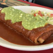 Crisp-fried chimichanga is smothered with red chile sauce and topped with guacamole.