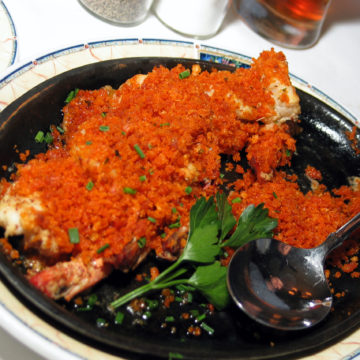 Shrimp are plastered with moist, seasoned breadcrumbs in a casserole dish.