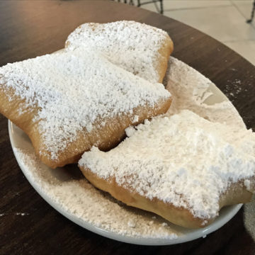 Puffy square pastries blanketed with powdered sugar