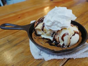 Huge, skillet-hot chocolate chip cookie comes adorned with ice cream, sauce, and whipped cream at Blue Canoe Cafe