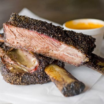 Two rib bones are laden with a great mass of spice-crusted, smoke-cooked beef