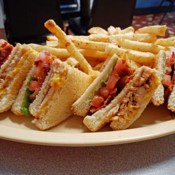 Quartered club sandwich holds turkey, bacon, lettuce & tomato, plus melted cheese.