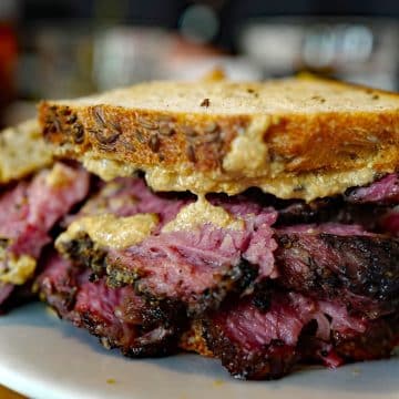 Slices of caraway-speckled rye hold luscious hunks and slices of pastrami, dressed with grainy mustard